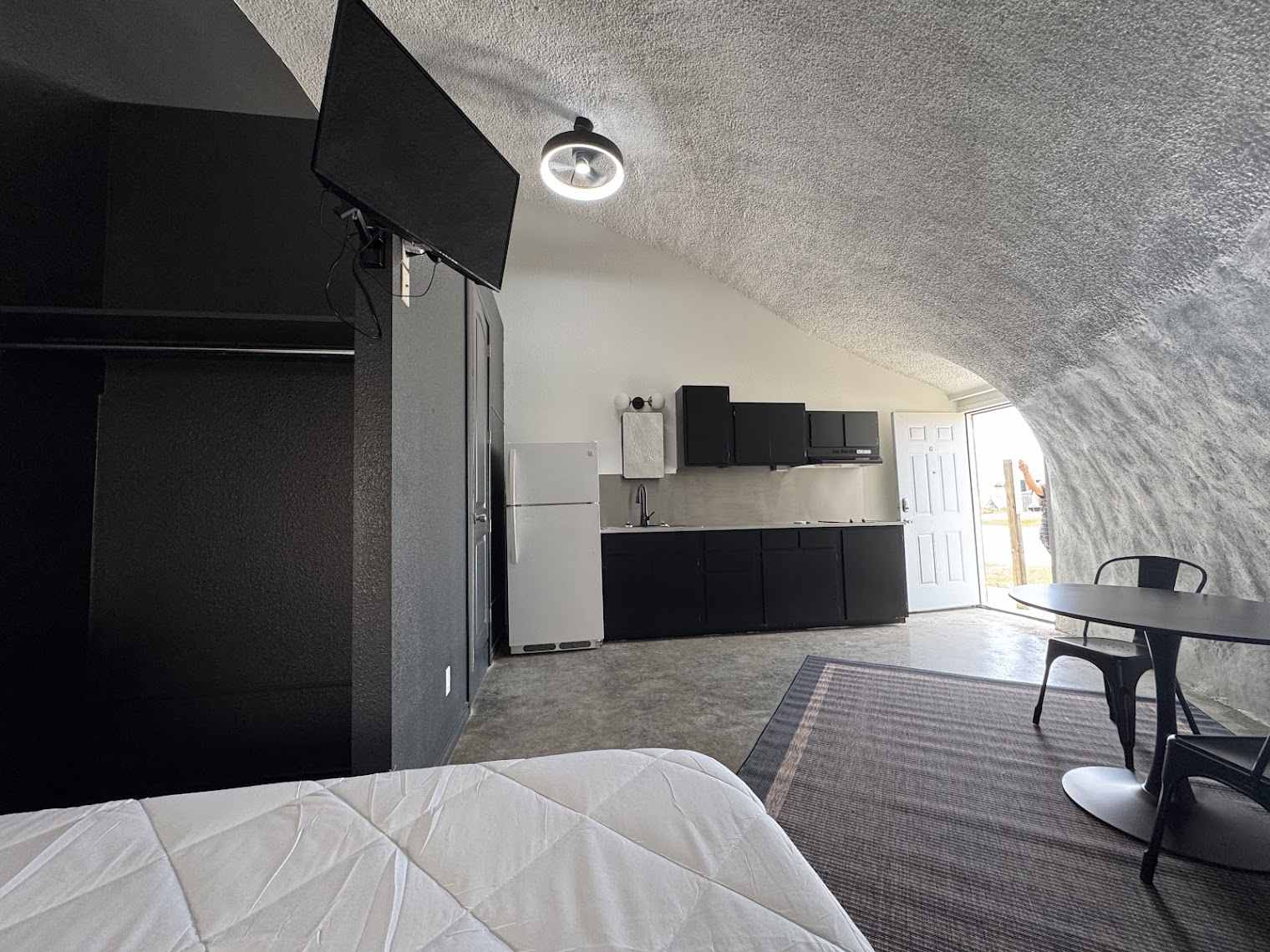Furnished dome room with smart TV, kitchen and entry door at The Domain