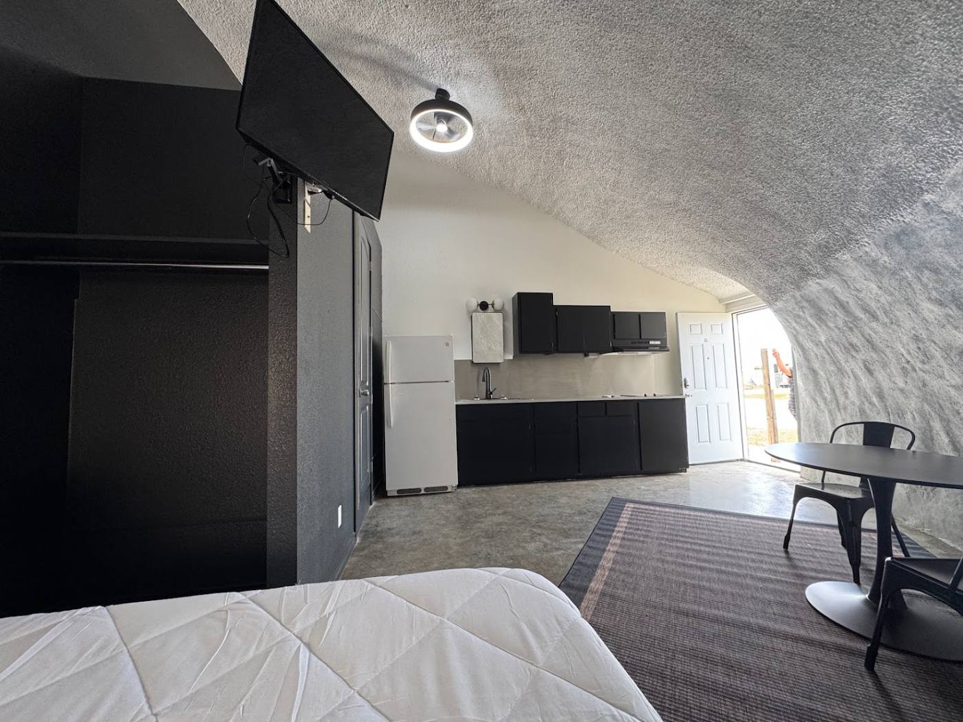 Furnished dome room with smart TV, kitchen and entry door at The Domain